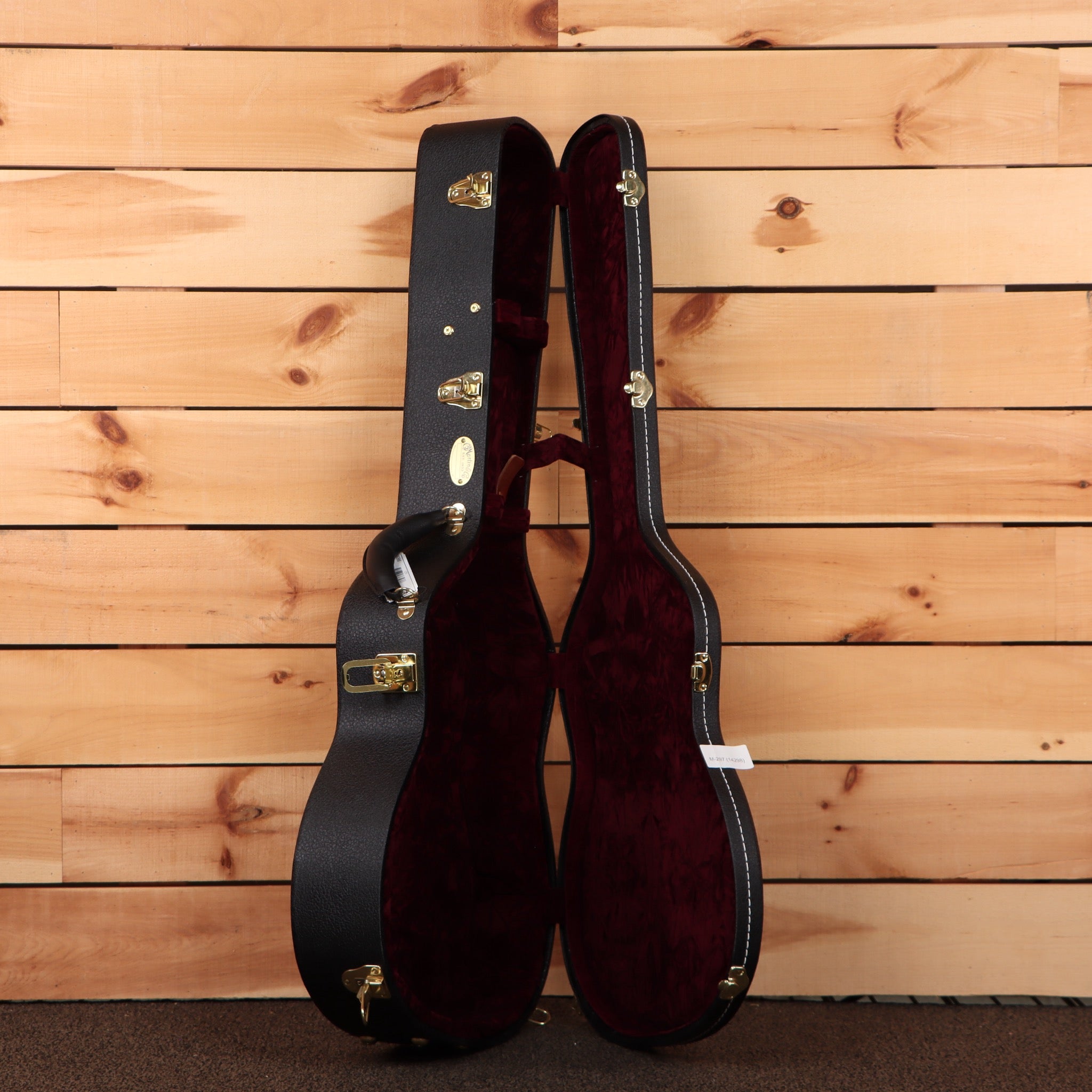 Martin Custom Shop NAMM 2026 Custom #5 hardshell guitar case open showing black exterior gold hardware and burgundy velvet in