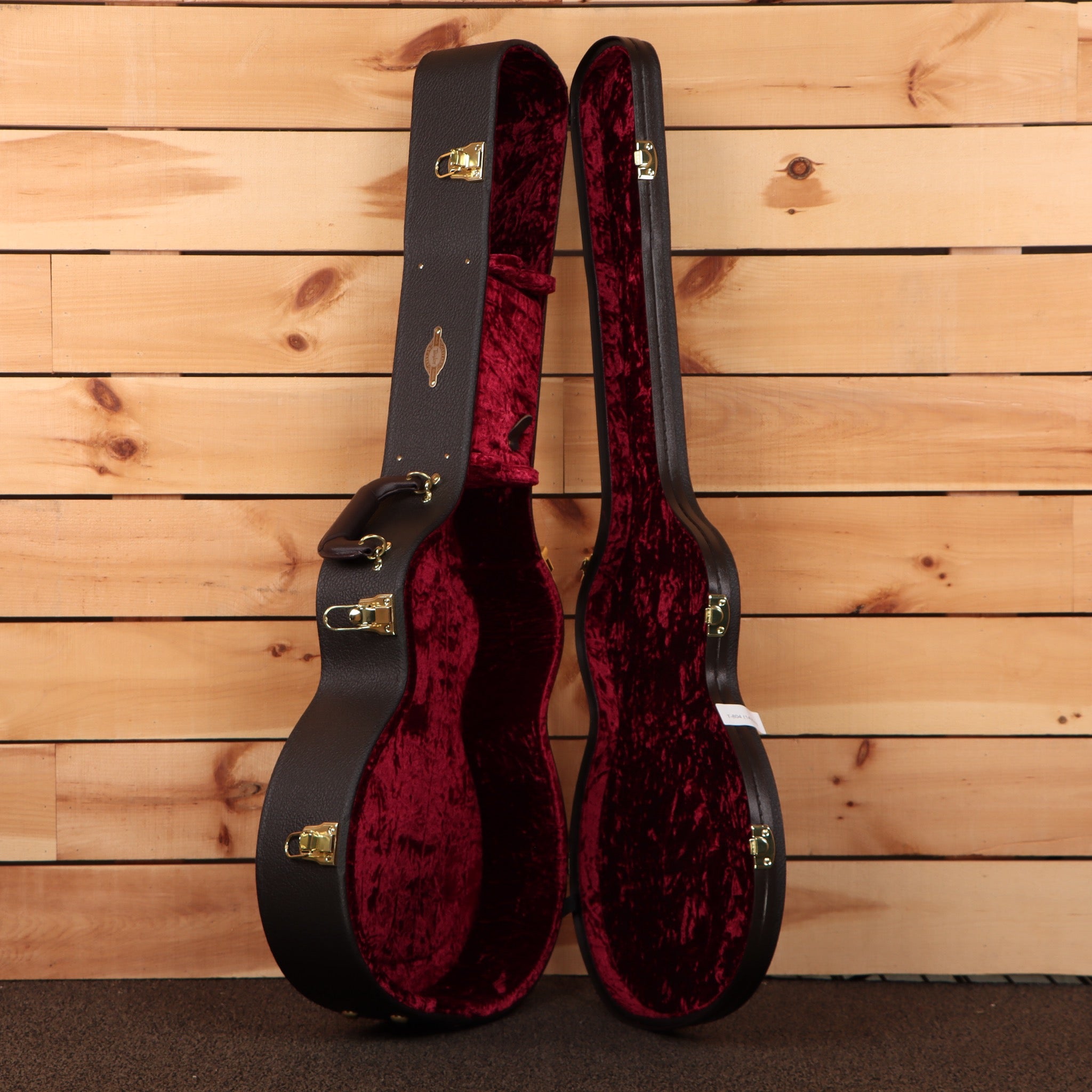 Taylor 314ce Next Generation hardshell guitar case open showing black exterior red velvet interior with gold latches
