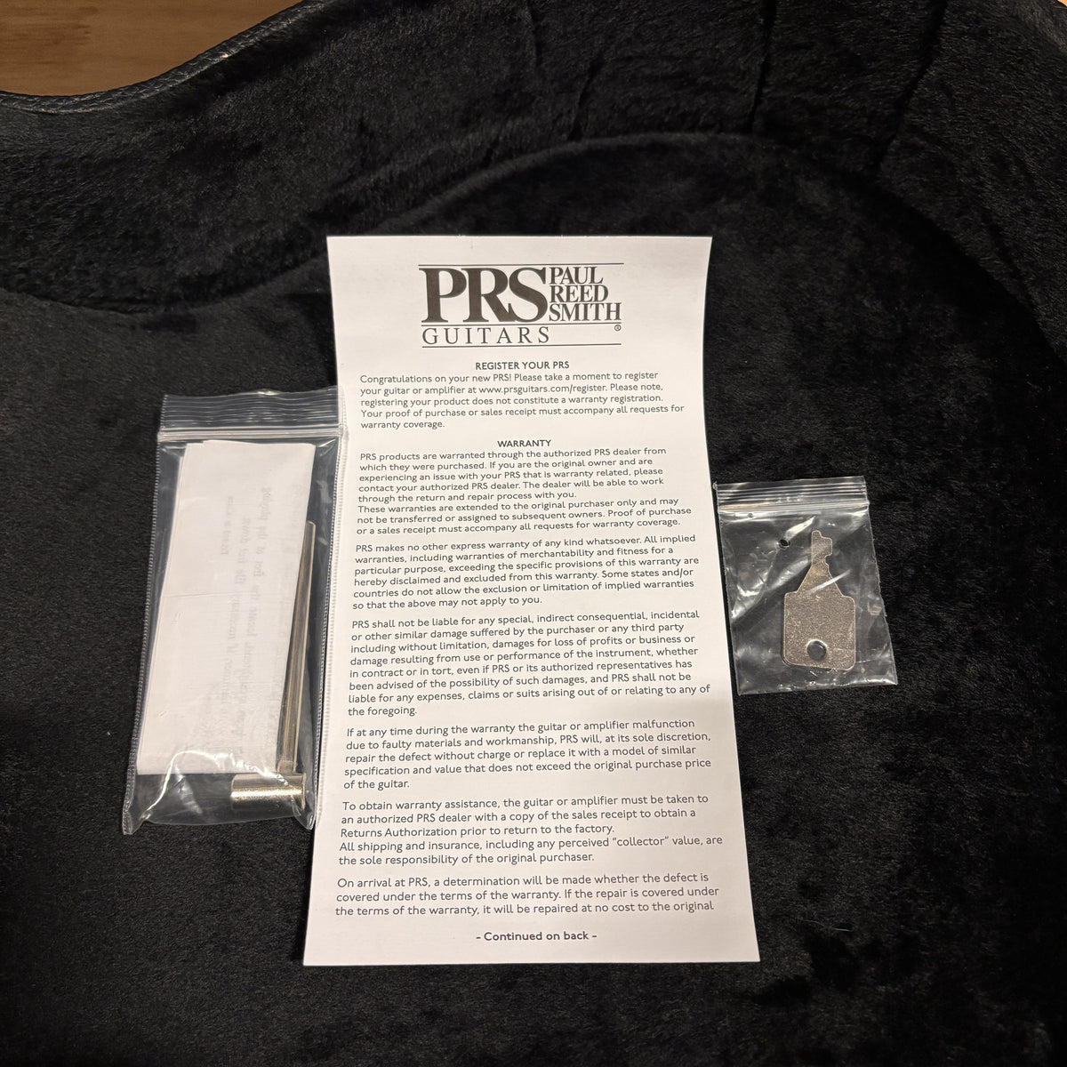 PRS SE Hollowbody Tobacco Sunburst guitar case interior with warranty card, truss rod tool, and strap button key